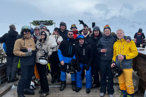 a group of people stand for a photo, they are wearing ski outfits